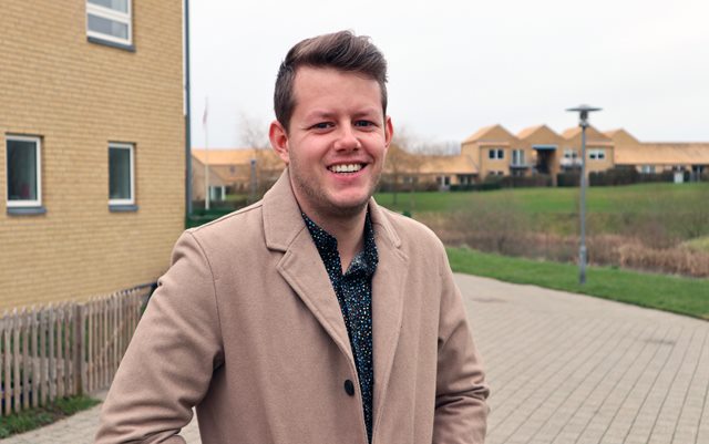 Alexander ved sit hjem med hule murstenshuse og grøn græsplæne i baggrunden