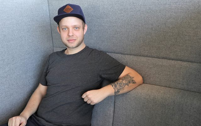 Serviceøkonomen Søren siddende i grå sofa med arm hvilende på puder