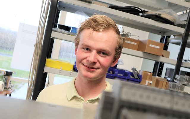Patrick med automationsudstyr i forgrund og baggrund fra værkstedet på campus Randers