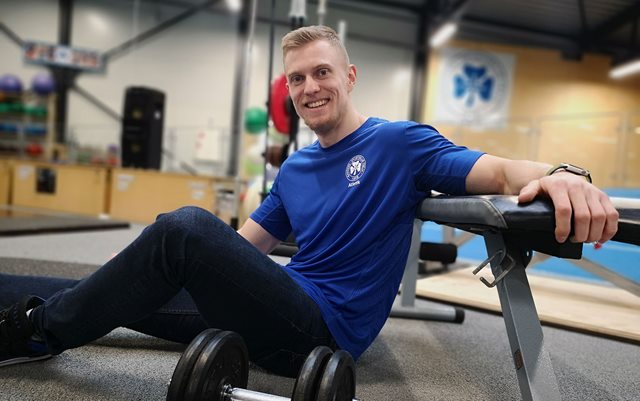 Datamatiker fra Erhvervsakademi Dania i Skive, Rasmus Madsen,sidder på gulvet og holder ved bænken, mens der foran ham ligger en håndvægt.