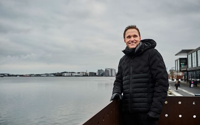 Underviser på Erhvervsakademi Dania Jørn står på havnen i Aalborg og kigger ud på fjorden med sort vinterjakke på i gråvejr