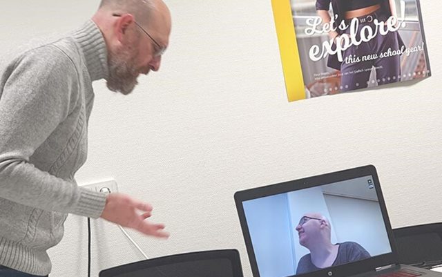 En mand taler til en anden mand på en skærm