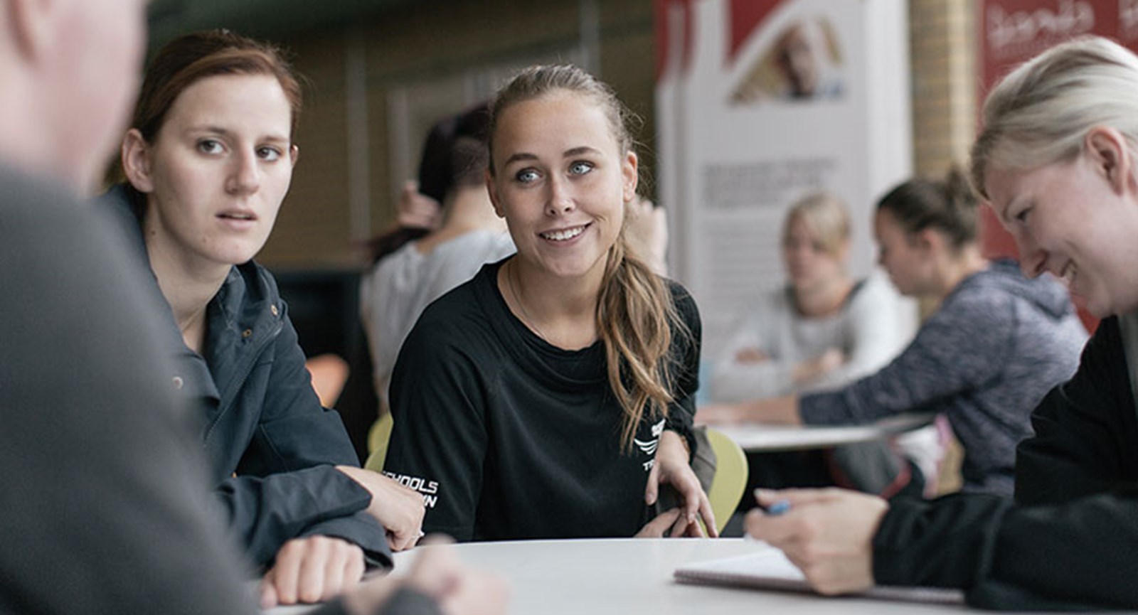 studerende rundt om et bord i samtale.