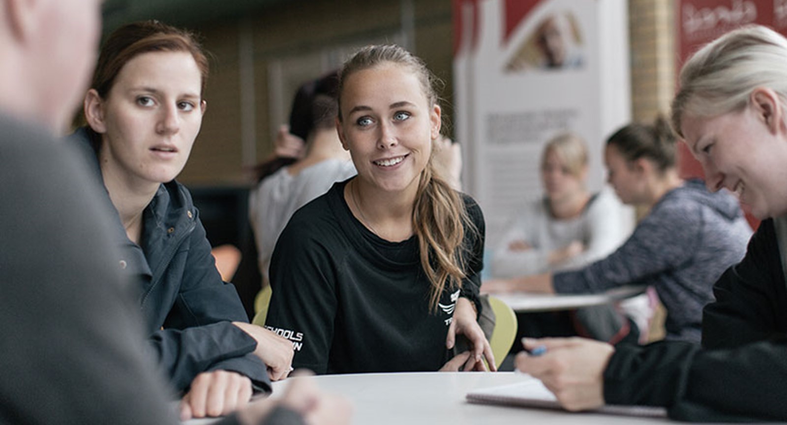 studerende rundt om et bord i samtale. 