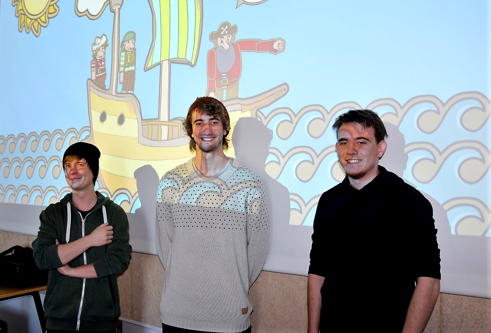 De tre Dania-Games studerende Henrik, Jonas og Daniels foran et skræmbillede af det øjetestspil, som de har udviklet