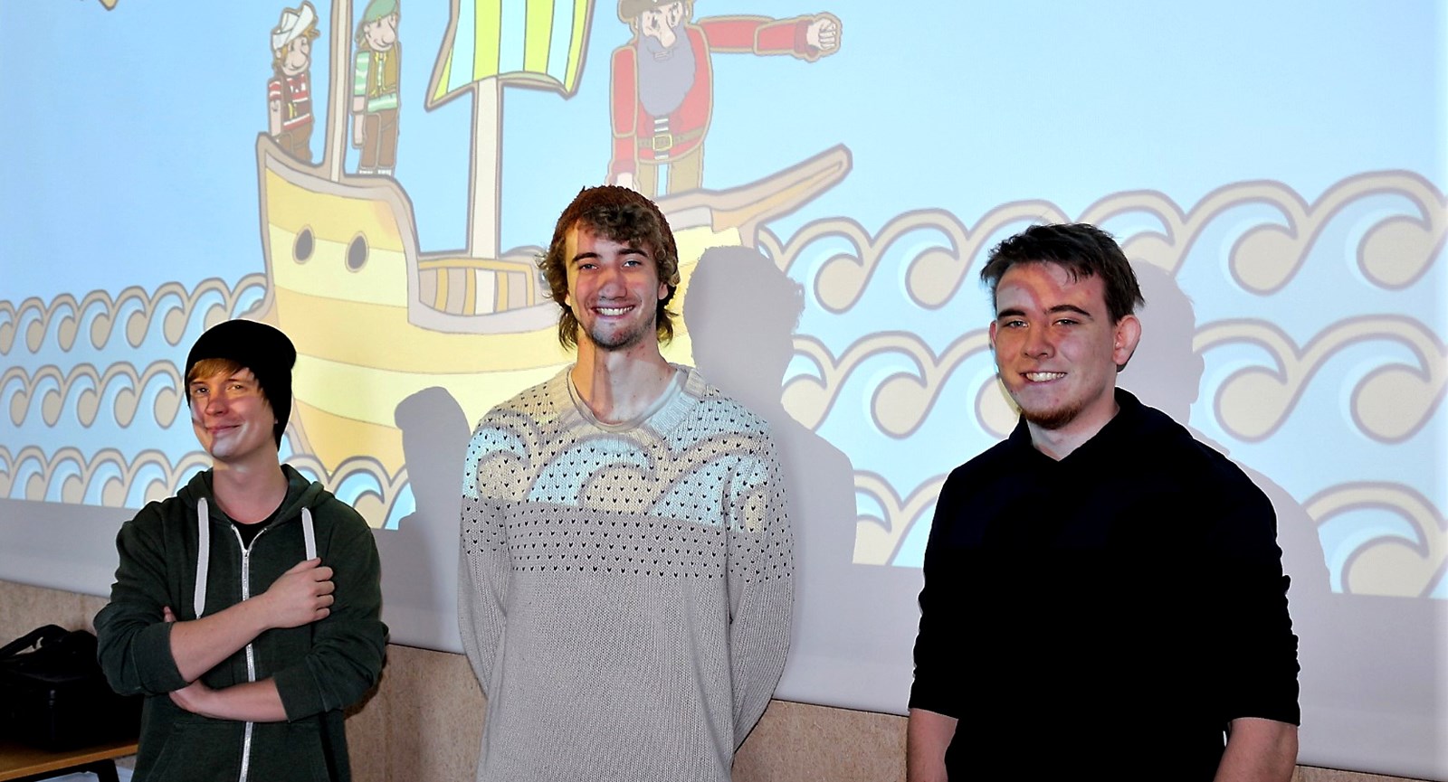 De tre Dania-Games studerende Henrik, Jonas og Daniels foran et skræmbillede af det øjetestspil, som de har udviklet