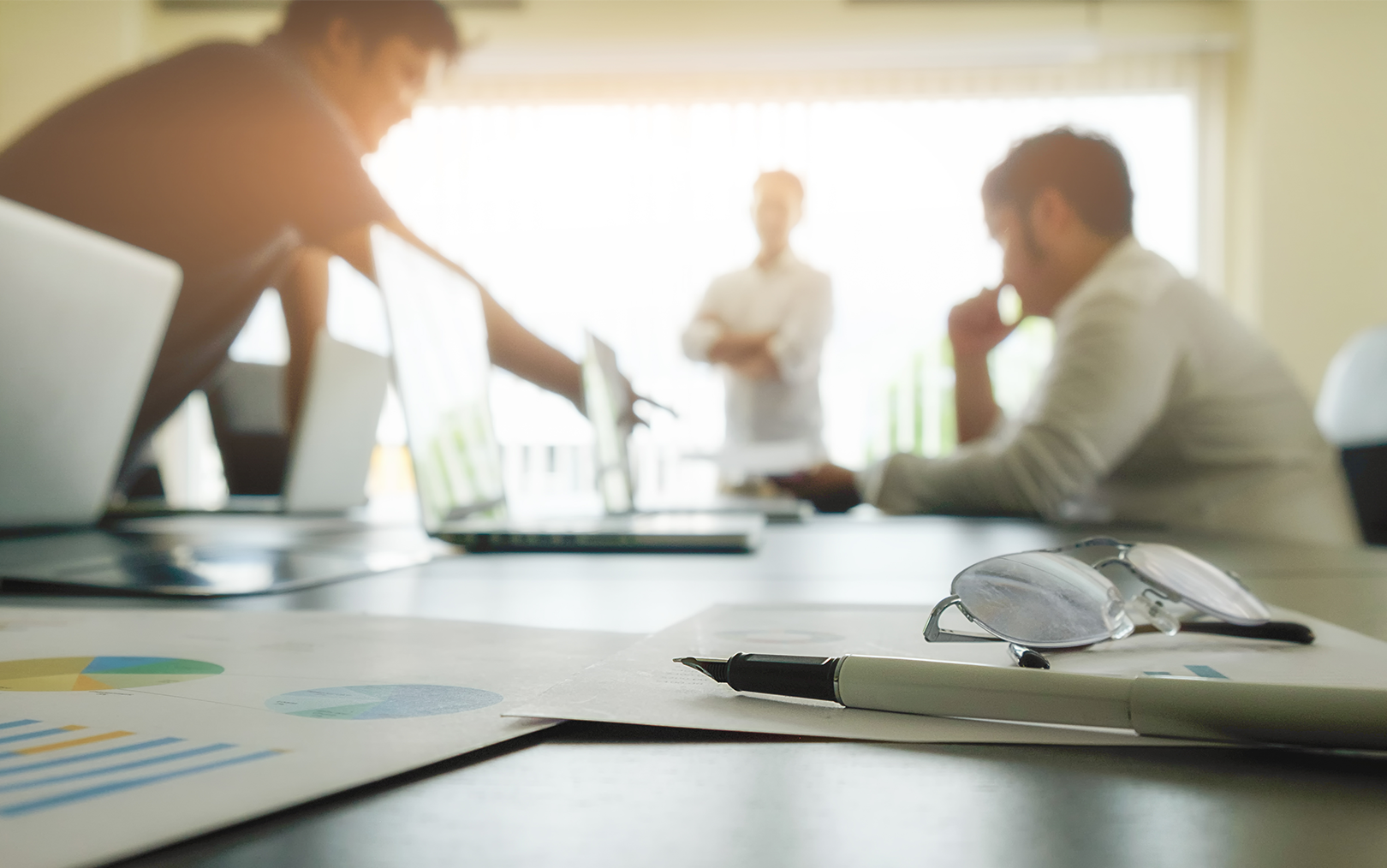 sløret billede af tre personer med et par briller og en kuglepen i front