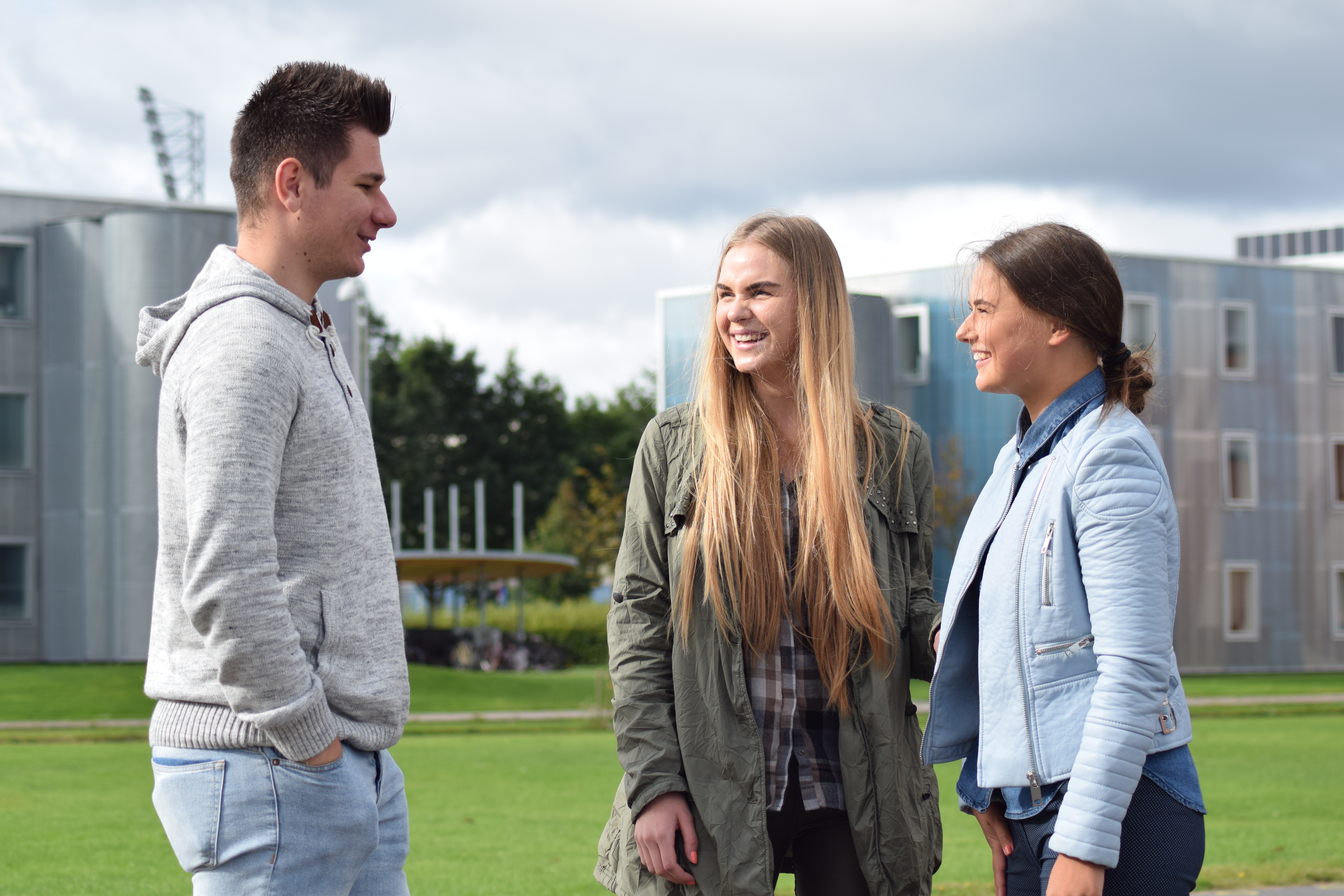 Studerende fra udlandet smiler til hinanden og bidrager til et internationalt studiemiljø hos Erhvervsakademi Dania