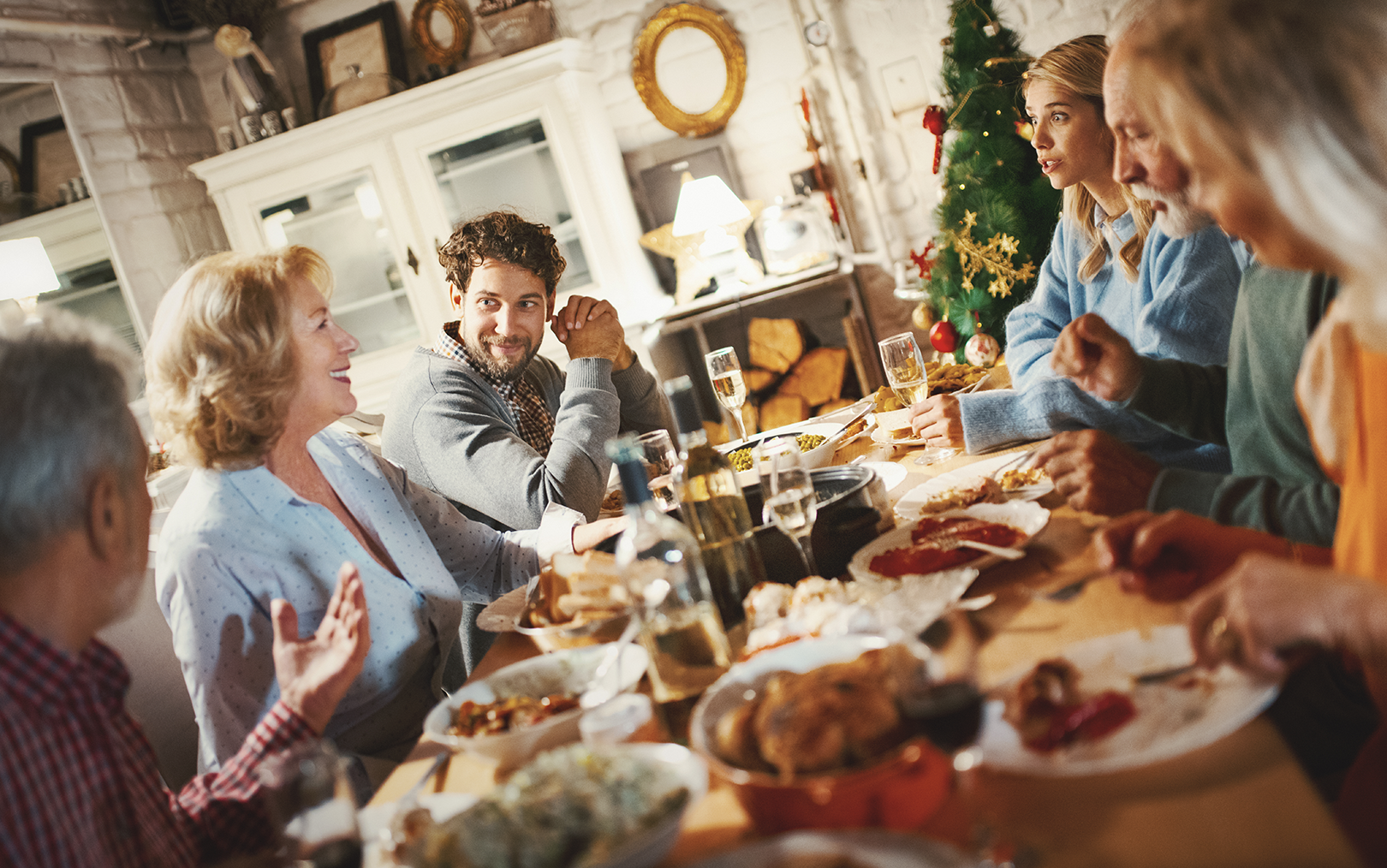 seks personer der sidder ved et middagsbord og spiser