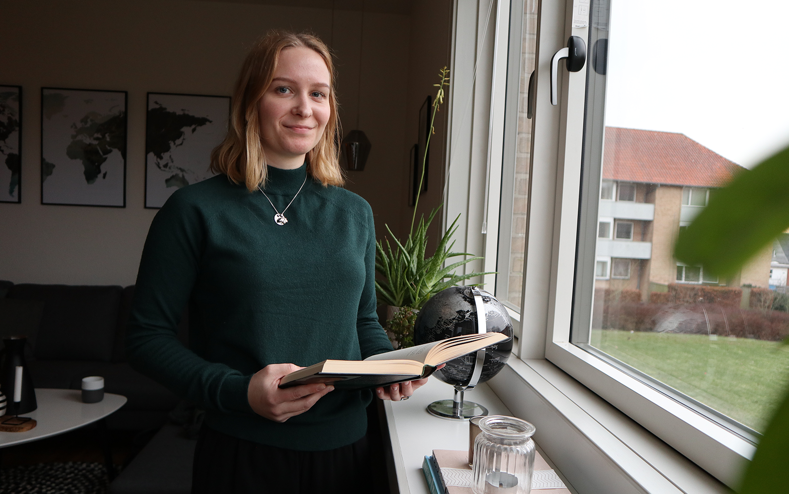 Markedsføringsøkonom Sarah Jensen i sit hjem med en bog i hånden tæt på vindue