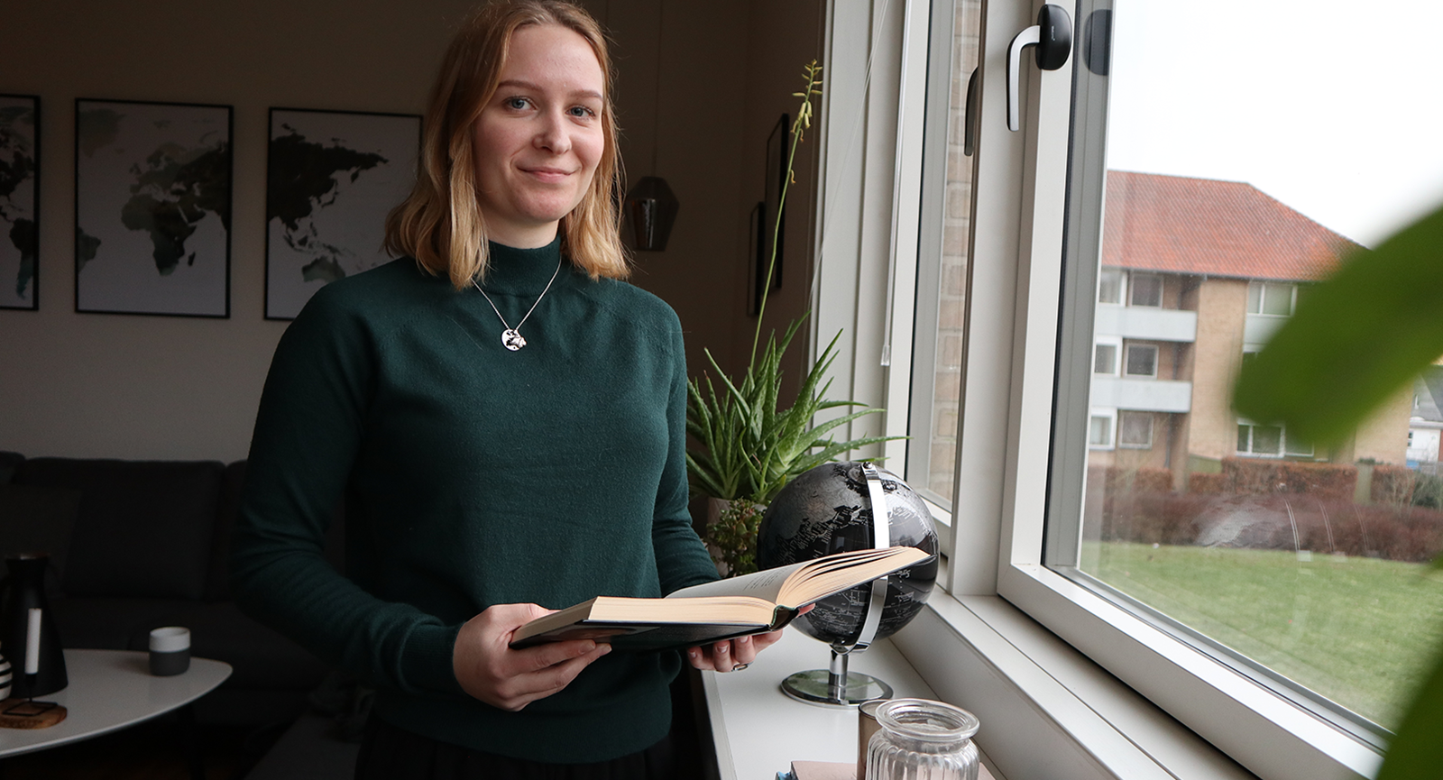 Markedsføringsøkonom Sarah Jensen i sit hjem med en bog i hånden tæt på vindue