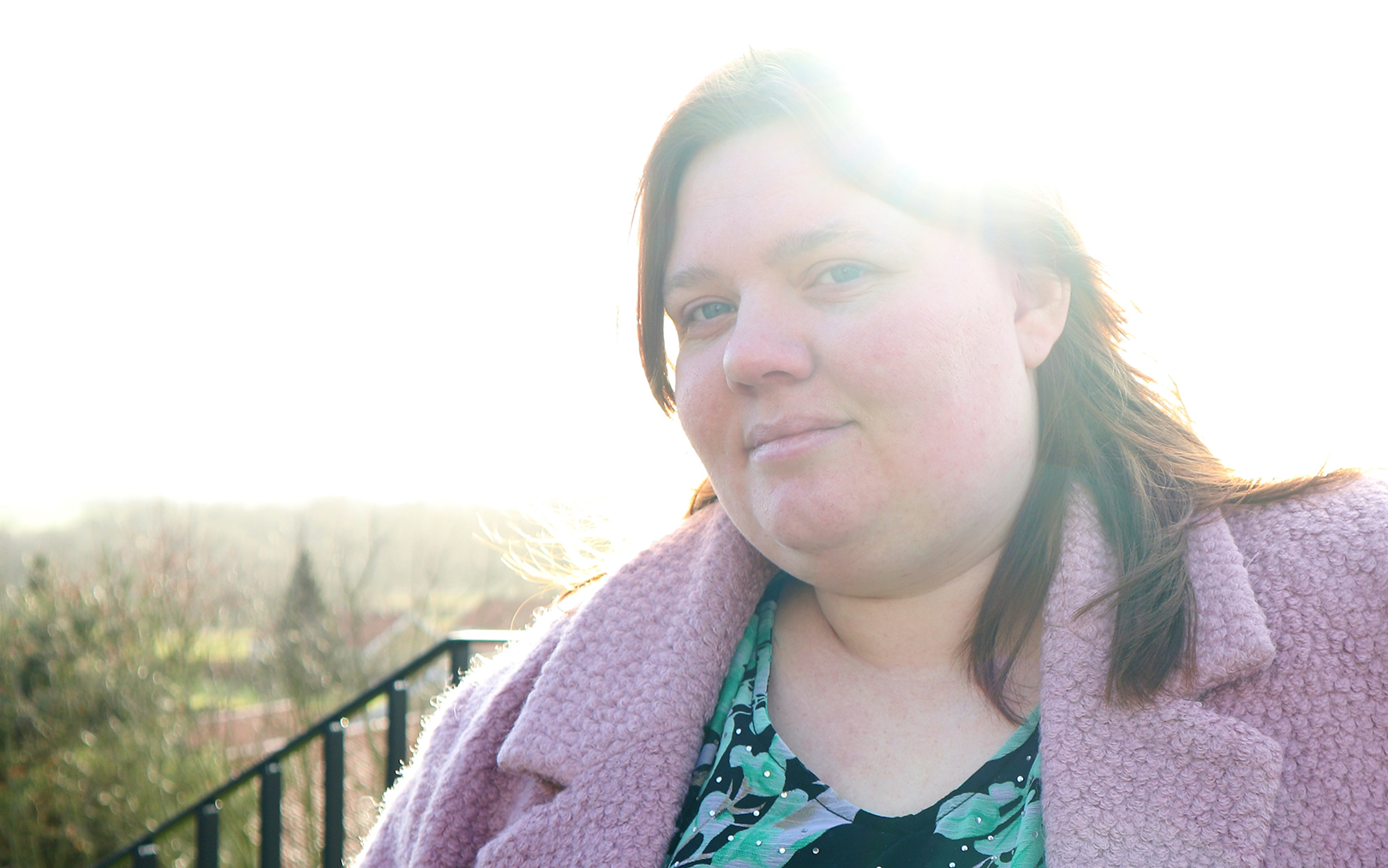 Produktionsteknolog Michele i lyserød jakke med modlys i kameraet