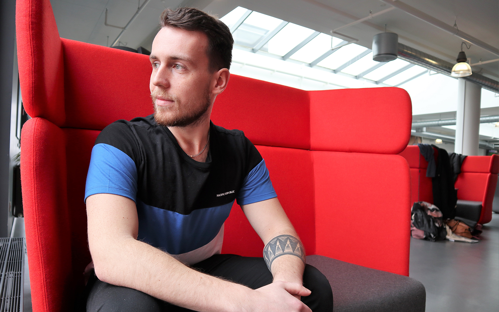 Pawel kigger ud af vinduet fra rød sofa på Danias campus i Viborg