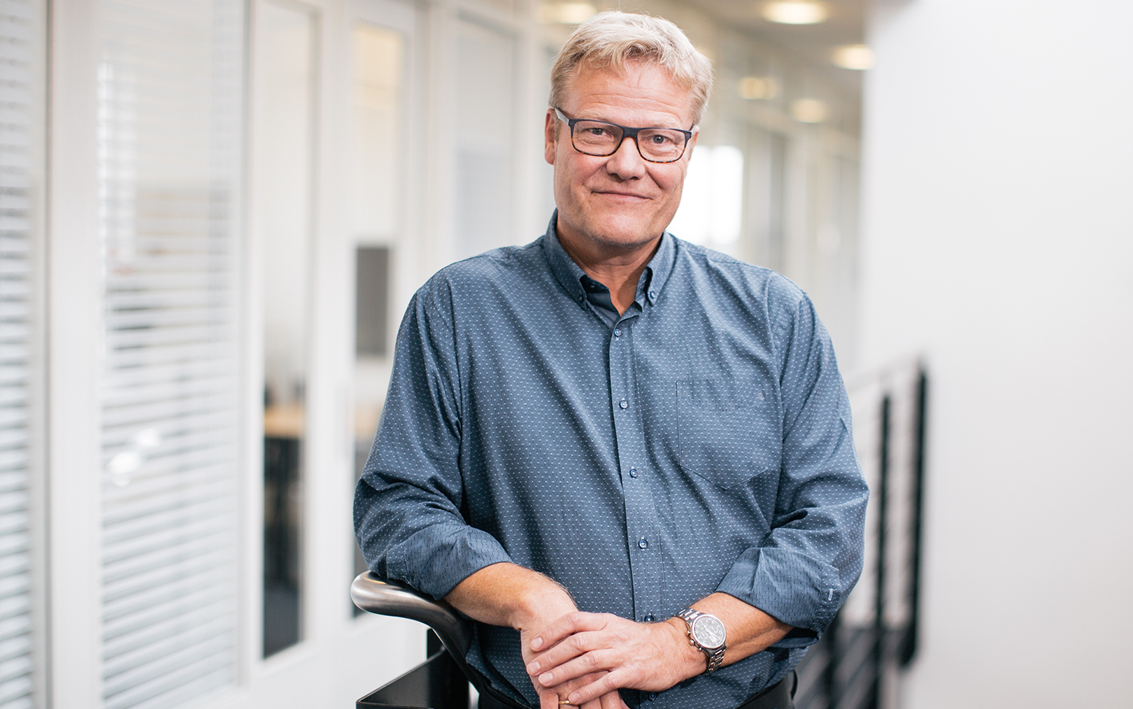 Rektor Anders Graae Rasmussen læner sig op af en trappe i gråblå skjorte