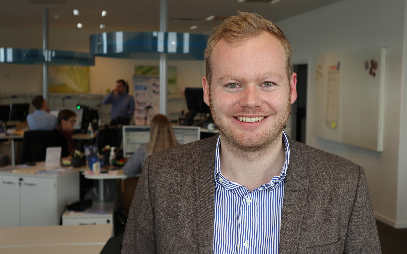 Rasmus Møller Jørgensen med kontor og kollegaer i baggrunden