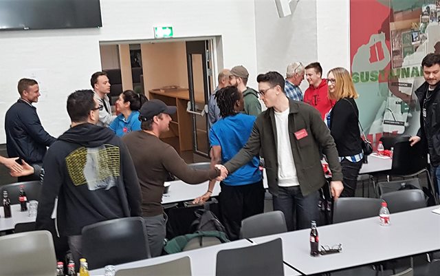 Studerende giver hinanden hånd i kantinen på Danias campus i Randers