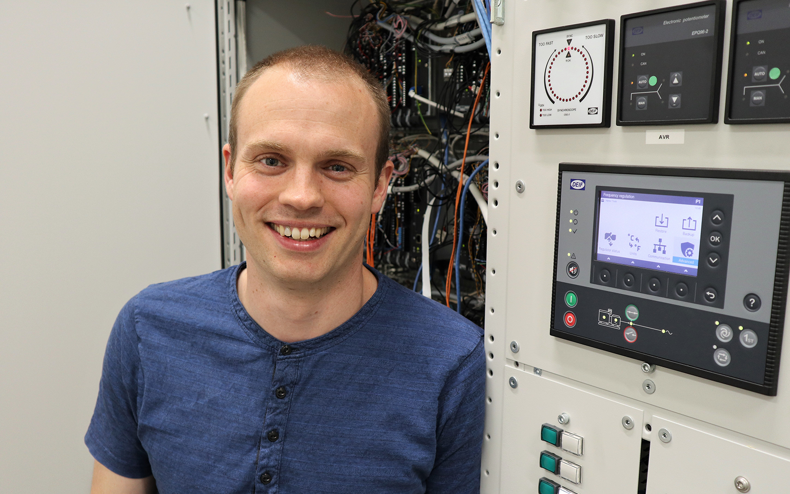 Kim læner sig op af et panel med knapper, skærm og ledninger