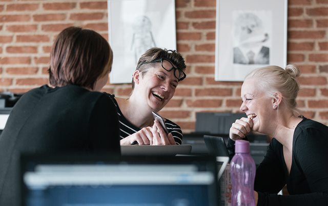 Kvinde viser telefon til anden kvinde og griner sammen på campus i Skive
