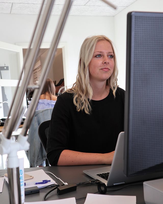 Handelsøkonom Kamilla sidder ved sit skrivebord  og kigger ind i skærmen, mens kollega sidder med ryggen til