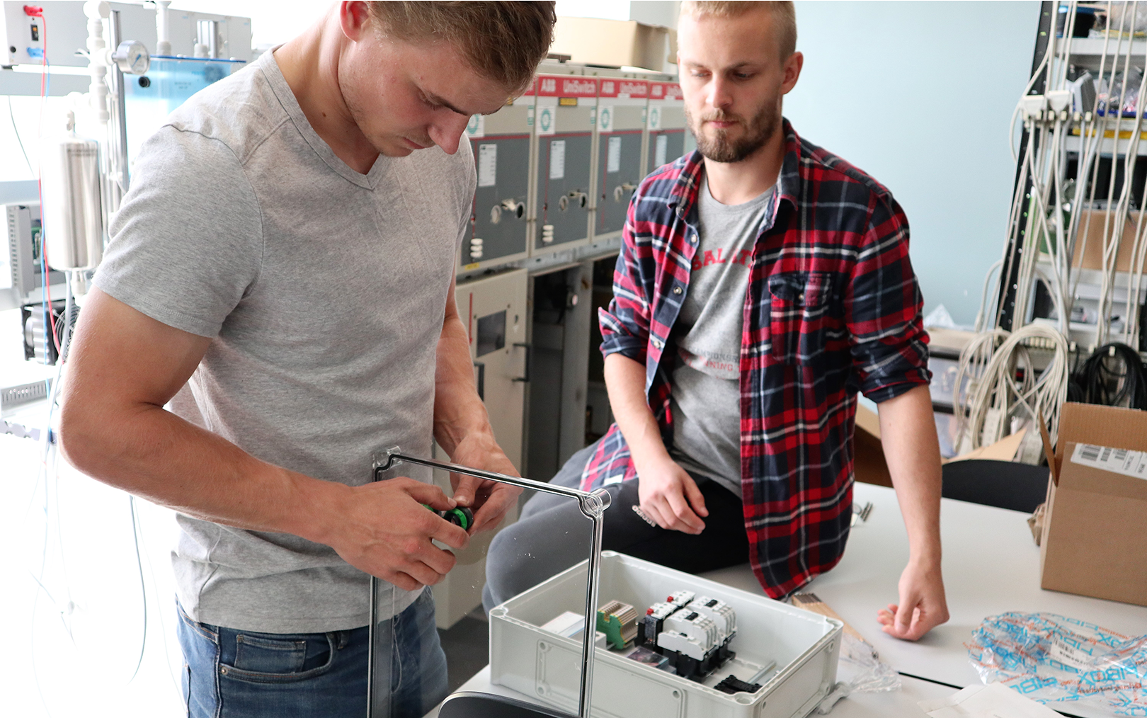 Automationsteknolog Max samler en el-tavle, mens Anders Bonde kigger på