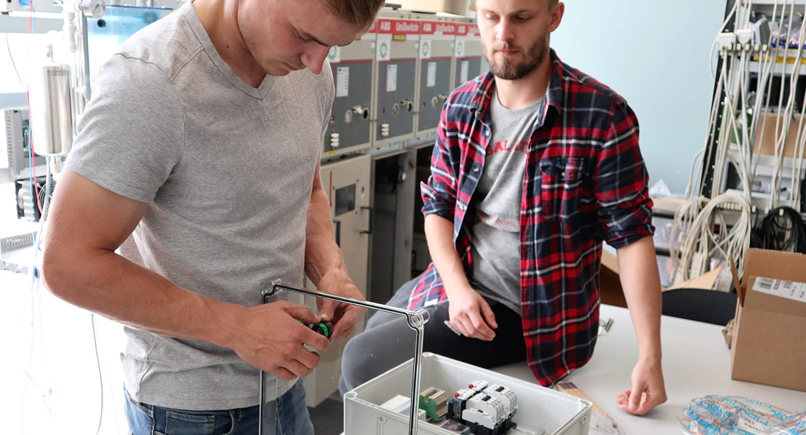 Automationsteknolog Max samler en el-tavle, mens Anders Bonde kigger på
