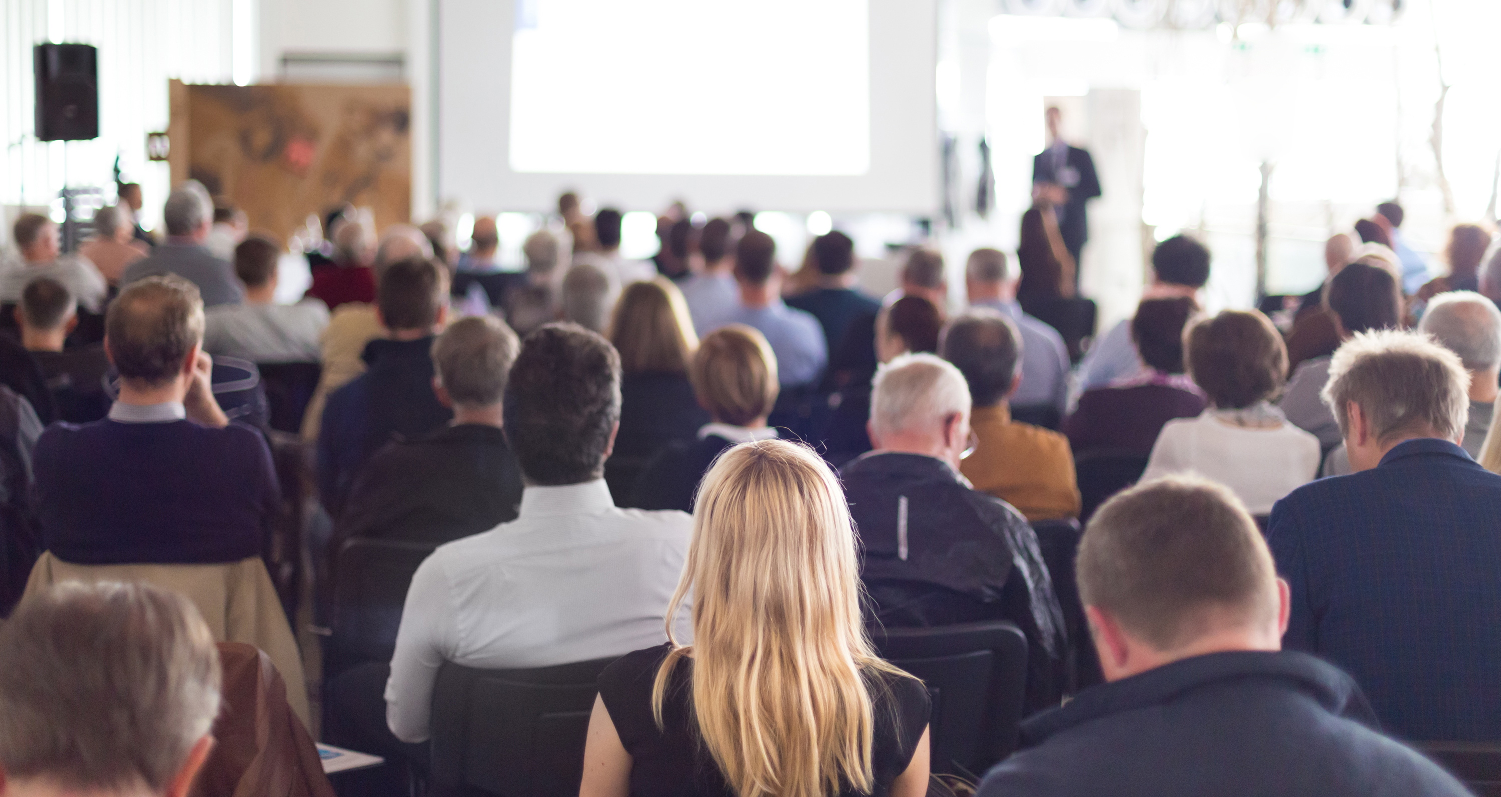 Mange mennesker kigger op mod et hvidt lærred, hvor alle vender med ryggen til dig