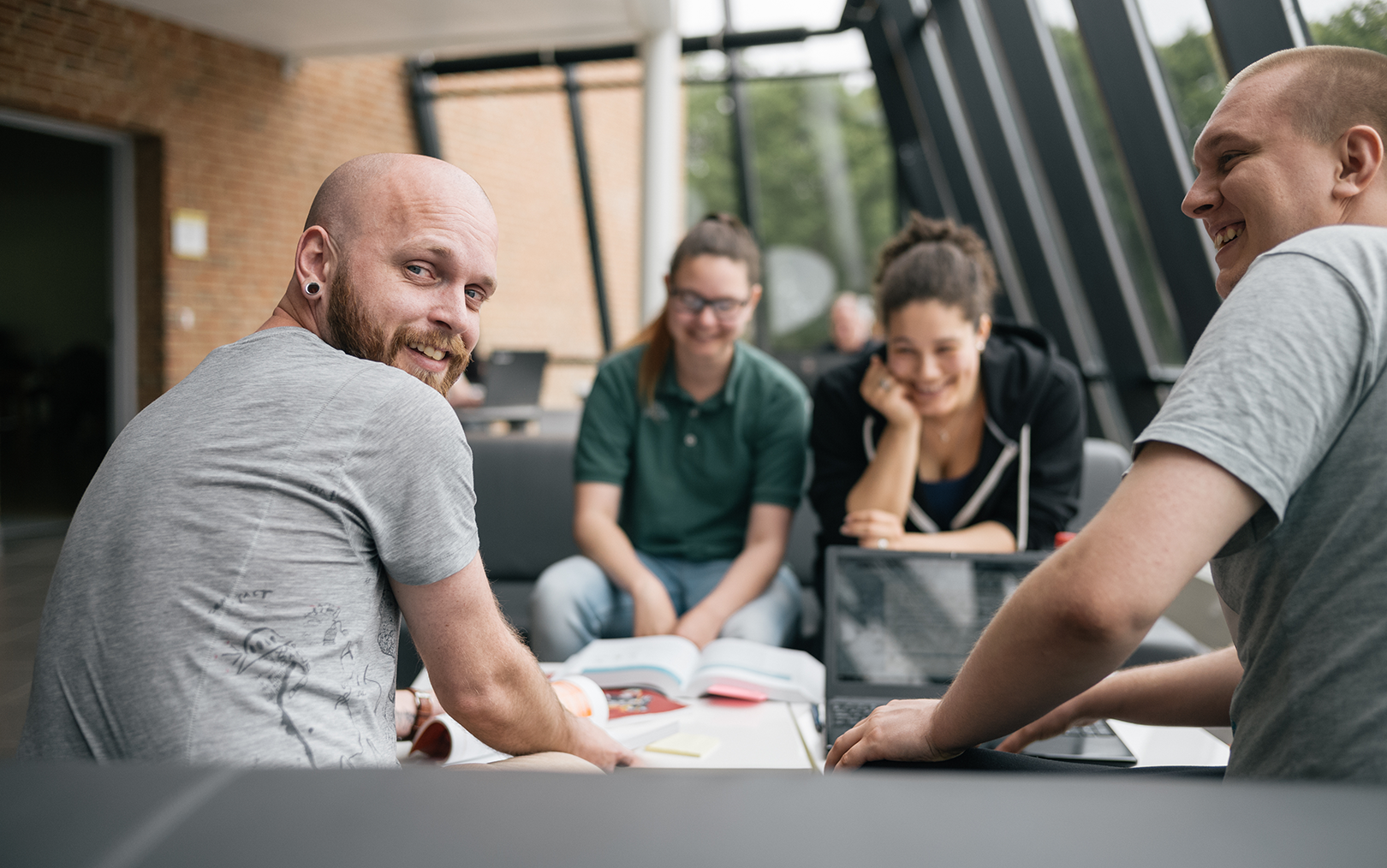 Fire studerende sidder i sofa i Skive og den ene fyr vender sig rundt og kigger på dig, mens de andre griner