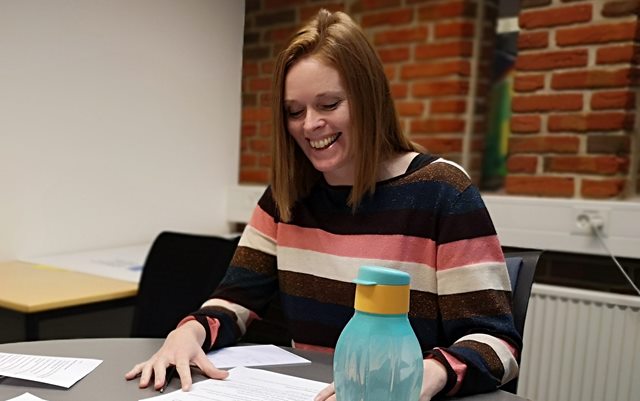 Gitte Larsen smiler ned i bordet, der er fuld af papirer fra uddannelsen til coach på Erhvervsakademi Dania i Skive