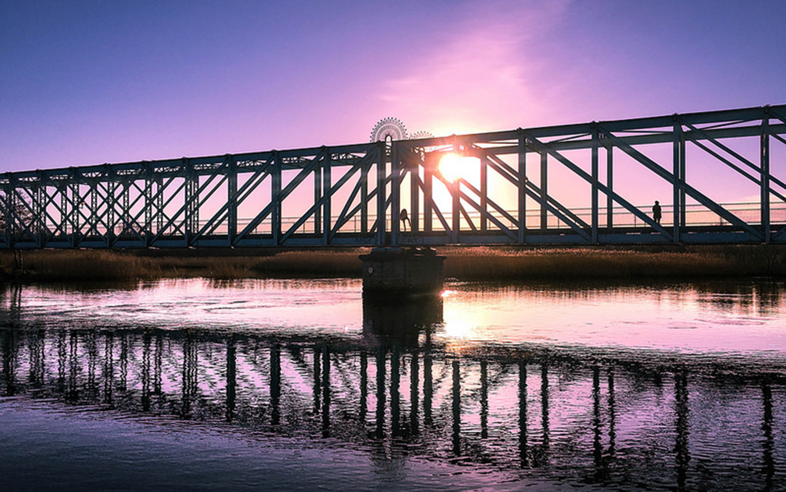Solnedgang i lilla og lyserødt over Randers Fjord med den blå bro i forgrunden