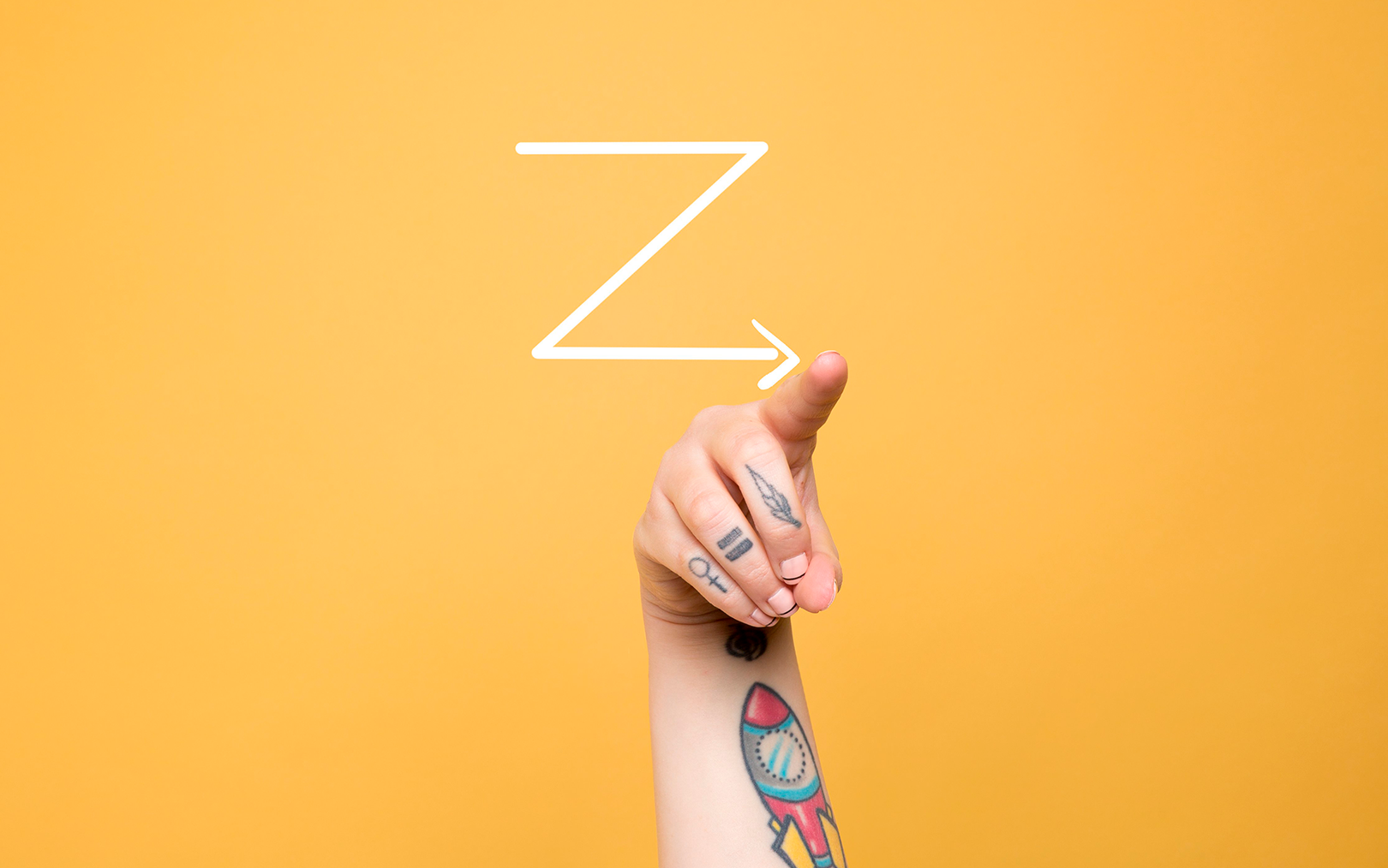 Bogstavet Z skrevet på karrygul baggrund og en arm med mange tatoveringer peger på enden af bagstavet