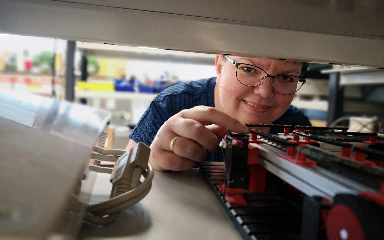 Automationsteknolog Pia rører ved en styring til robot, mens hun smiler til dig