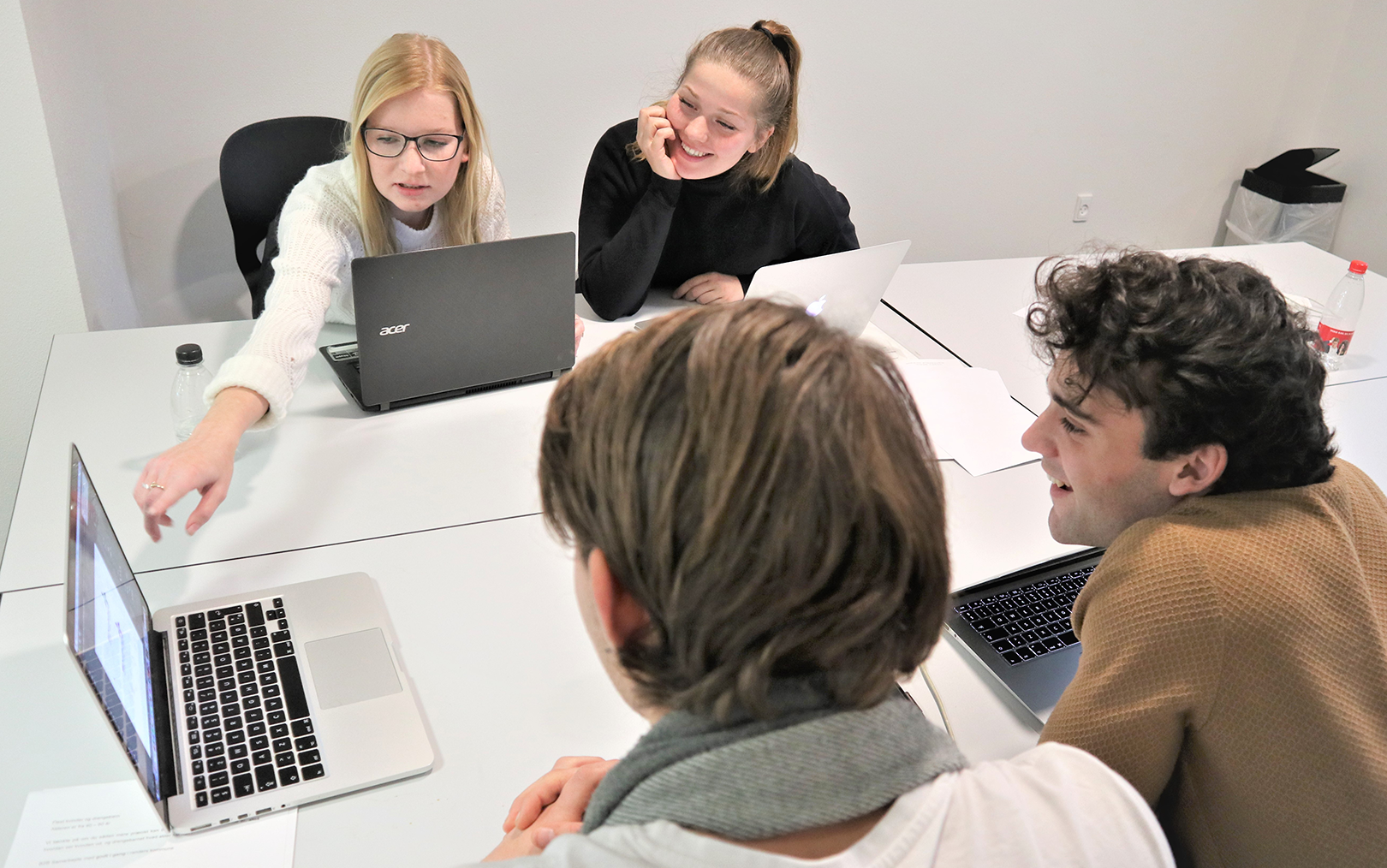 Markedsføringsøkonom peger på computer, mens resten af hendes gruppe smiler