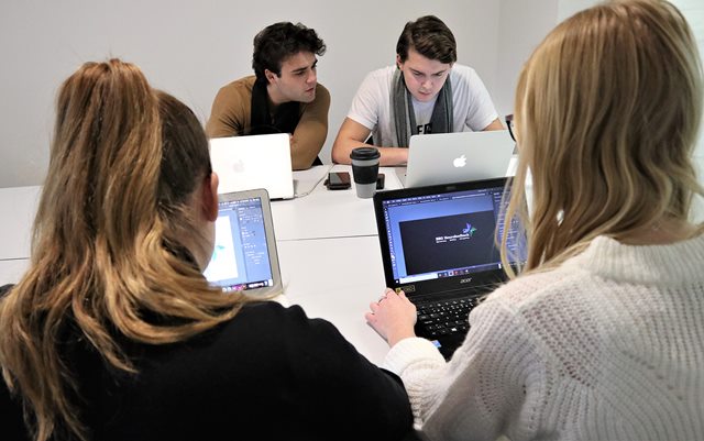 Rasmus Malik kigger på Nickolas Jensens computer med sine medstuderende på markedsføringsøkonom-studiet i forgrunden