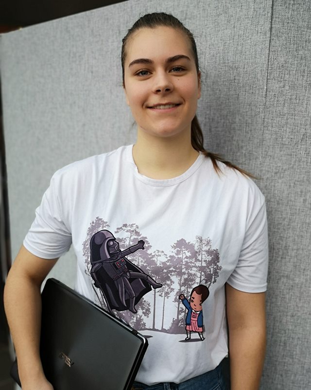 Datamatiker-studerende Helena Madsen smiler, mens hun holder en bærbar computer under armen.