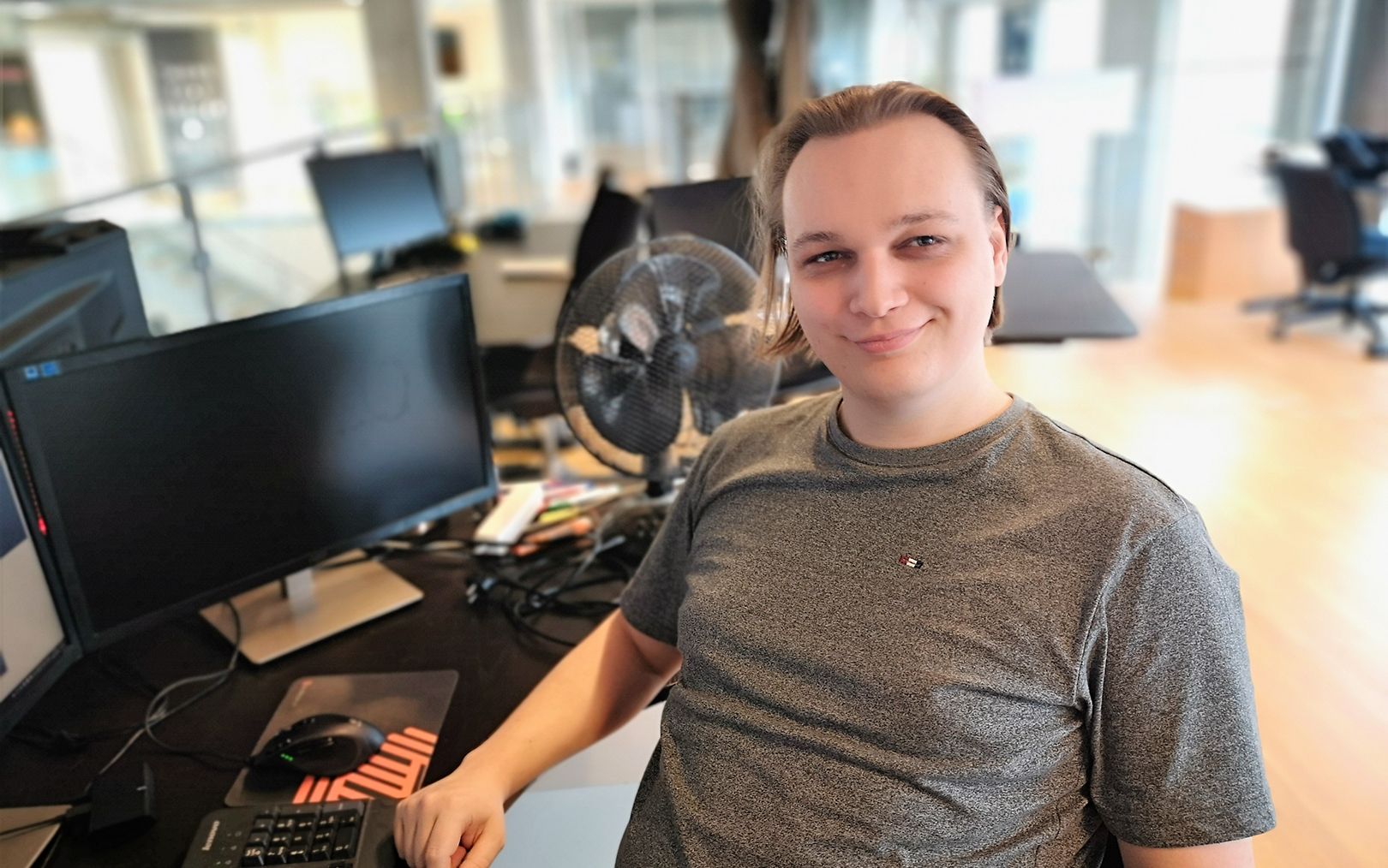 Studerende Mikkel DockWeiler Sørensen sidder ved sit skrivebord med sin computer og smiler til kameraet.