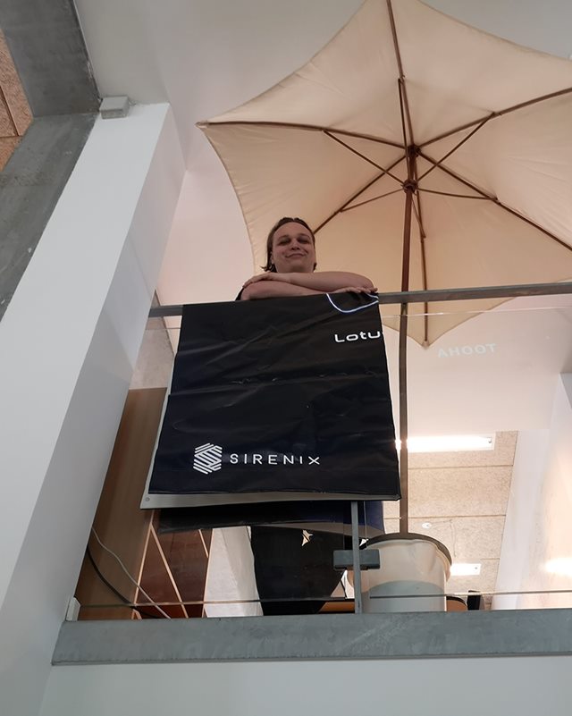 Studerende Mikkel DockWeiler Sørensen kigger ned oppe fra første sal, imens han smiler og læner sig op ad et sort håndklæde med påskriften 'Sirenex', der hænger over et gelænder. 