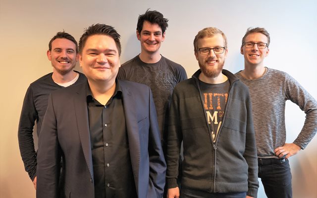 Fem mænd står og smiler direkte ind i kameraet. De fem mænd har til sammen udviklet computerspillet Ember Sword. Mændene hedder: Daniel Kaldahl Skjølstrup, Mark Laursen, Joris Huijbregts, Sune Thorsen og Bjarke Ørrild.