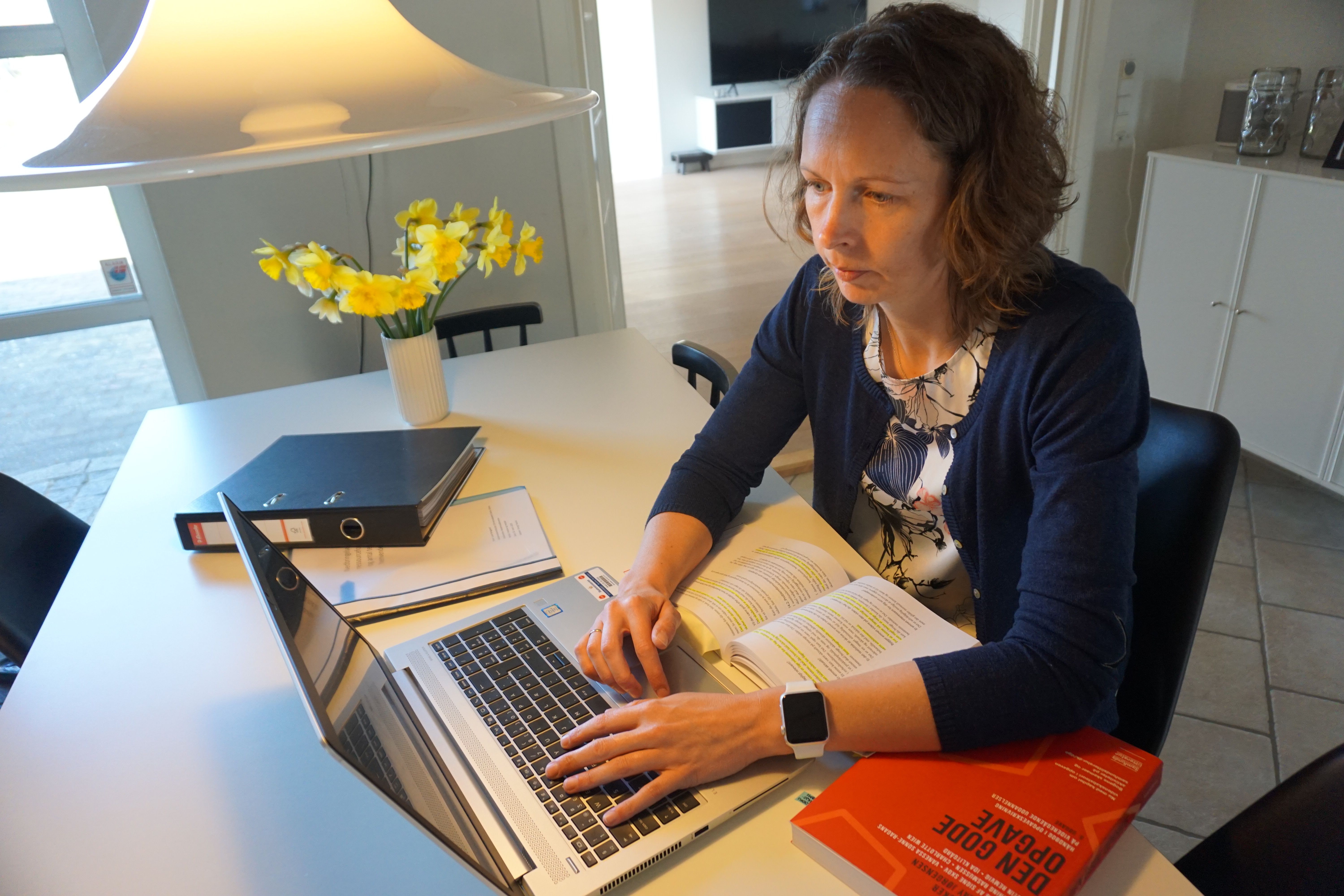 Sagsbehandler Luise Korsgaard sidder ved sit spisebord foran en bærbar computer og arbejder koncentreret.