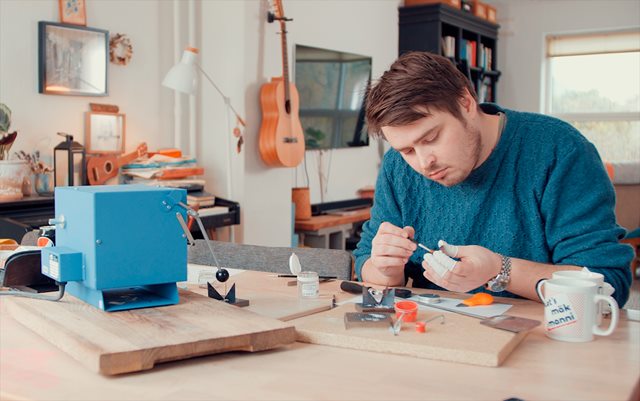 Iværksætter Kasper Reisner sidder ved et arbejdsbord og arbejder koncentreret med noget småt præcisionsværktøj.
