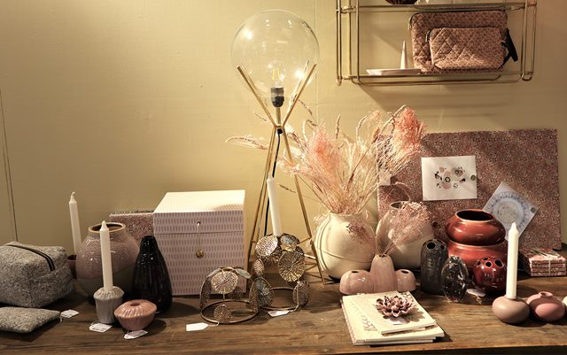 Et udstillingsbord med vaser, lysestager og andre pynteting i et showroom hos virksomheden F&H.