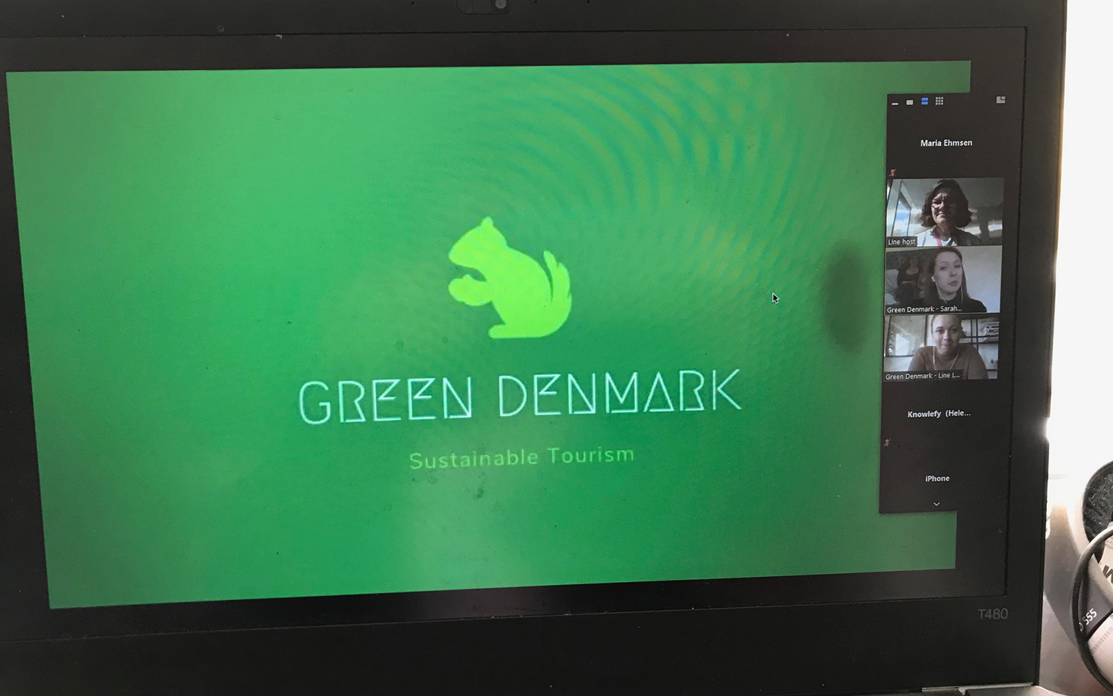 Nærbillede af en computerskærm med grøn baggrundsfarve og et motiv af et lysegrønt egern og påskriften 'Green Denmark'.