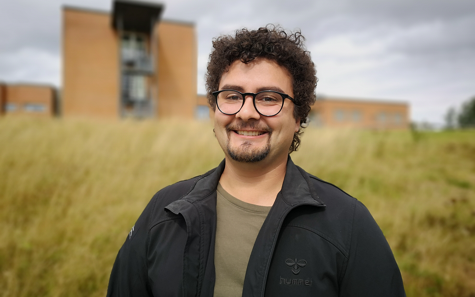 Mand smiler foran campus