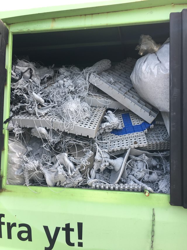 Et nærbillede af en affaldscontainer fyldt med plastikdele fra produktion af skridsikre gulve.