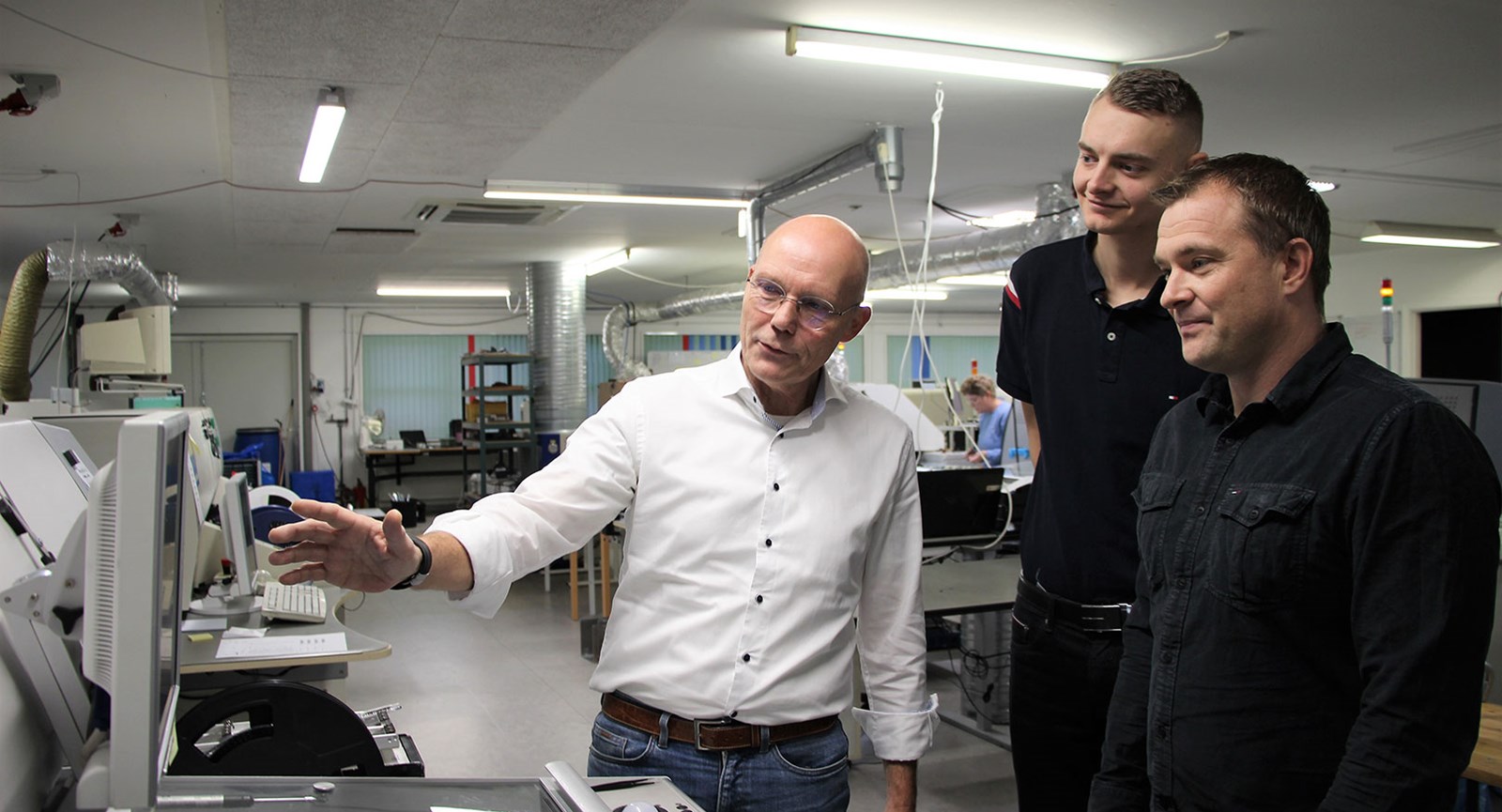 Ole Stabell viser nogle af de robotter frem, som Danotek har. Produktionsteknolog studerende Simon Jensen (midten) og Lars Bastrup er glade for samarbejdet og at prøve deres teori af i praksis på Erhvervsakademi Dania