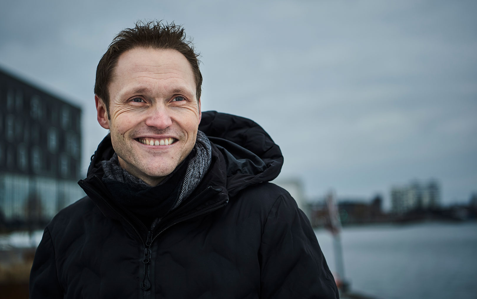 Jørn Byridsen er kåret som årets bedste underviser på Erhvervsakademi Dania står med jakke og kigger ud over havnen i Aalborg