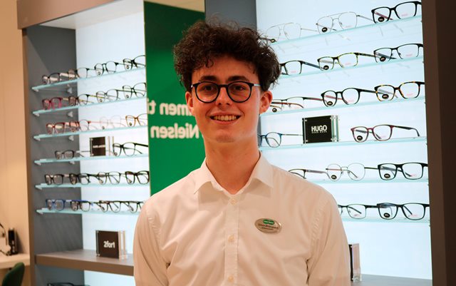 Simon Nørskov Østergaard i Louis Nielsen-butikken i Viborg foran en masse briller, der vil læse til optometrist aka optiker