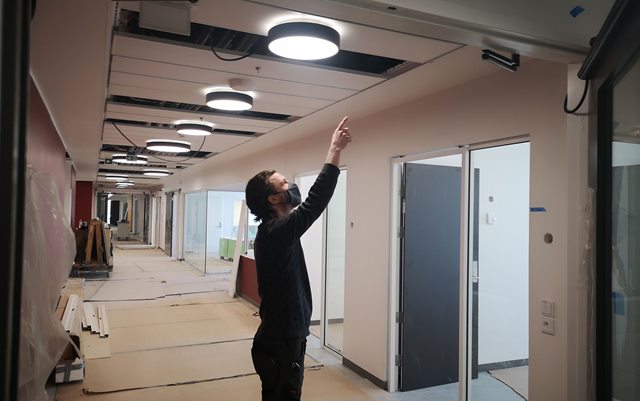 El-installatør Lars Krab peger på ledningsbakker i loftet på det kommende sygehus i Gødstrup