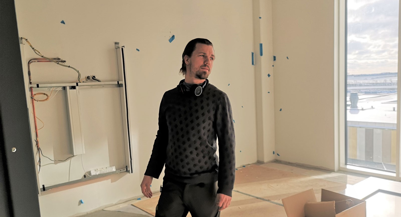 El-installatør fra Erhvervsakademi Dania Lars Krab står på en stue på det kommende supersygehus ved Herning. Der er blå prikker på væggen og kasse på gulvet, mens solen skinner ind af vinduet