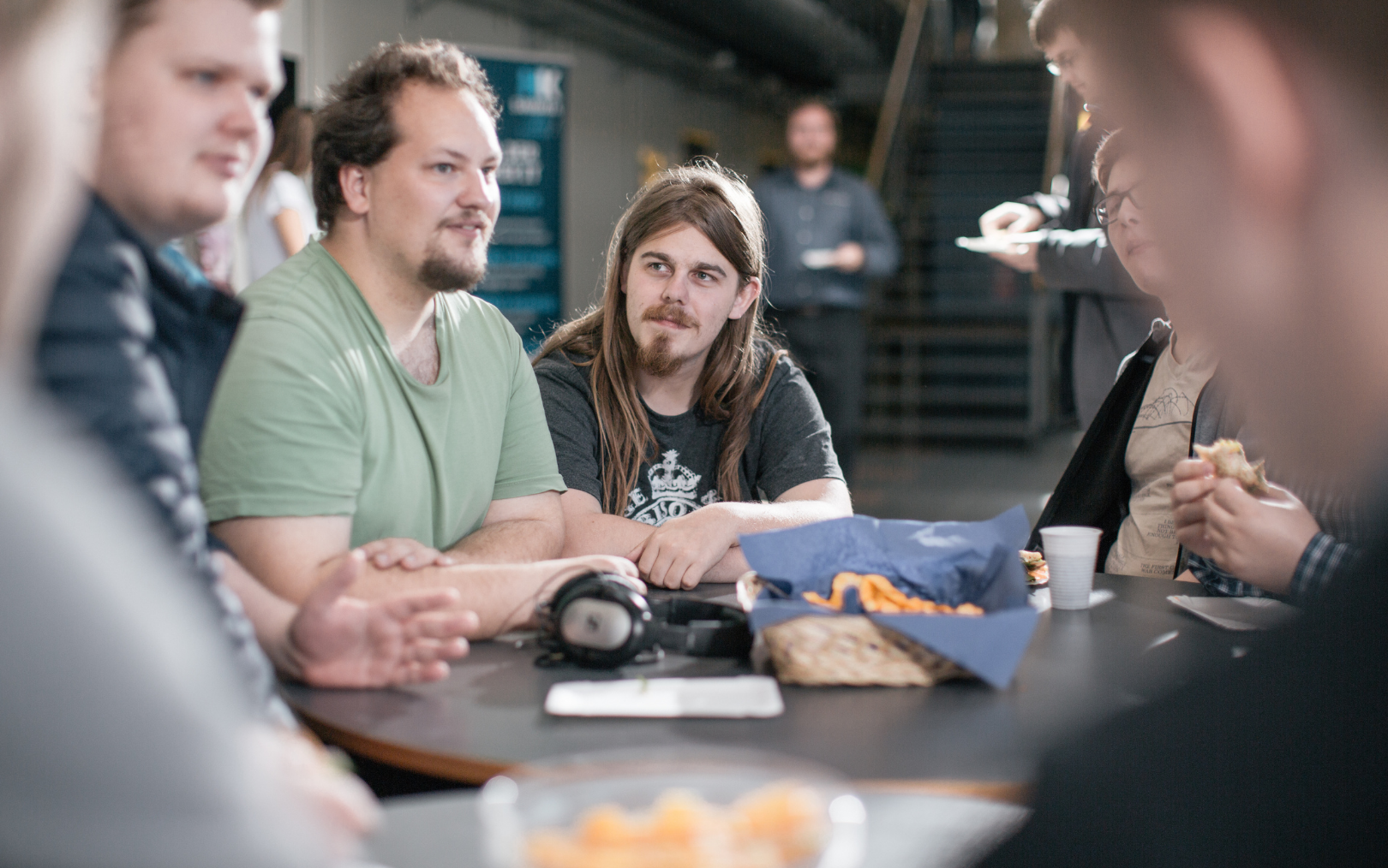 En fyr med langt hår sidder for enden af et bord i fællesområdet ved Erhvervsakademi Dania i Grenaa