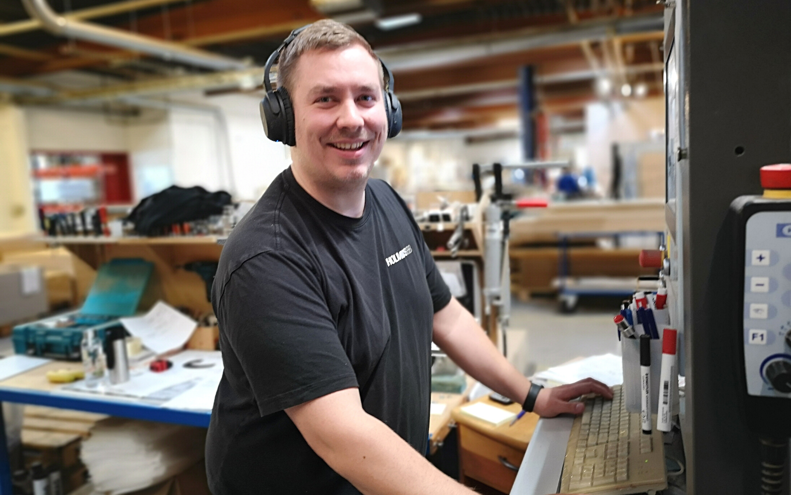 Kasper Bukdahl smiler, mens han står ved sin maskine ved Holmris B8